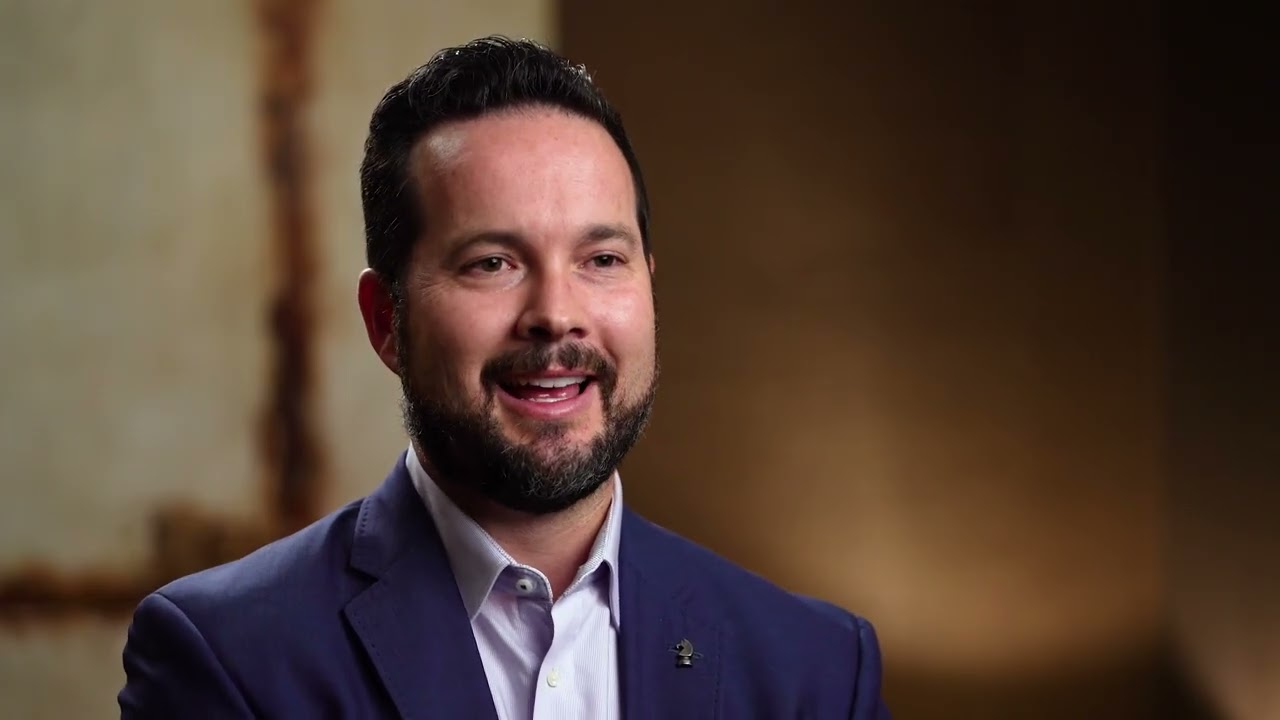 Dr. Joseph Field, a cosmetic and implant dental specialist, smiling during a video interview.