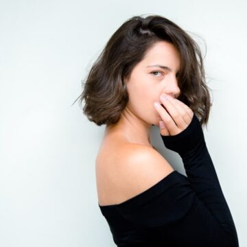 Maria-Dinulescu Professional headshot of a woman with a soft expression, wearing an off-shoulder black top, captured by Coldea Productions.