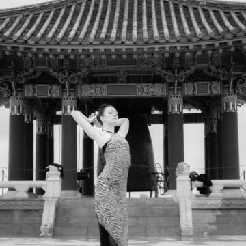 Black and white portrait of a woman in an elegant pose in front of the Korean Friendship Bell, blending fashion and dance, photographed by Coldea Productions.