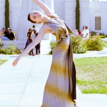 Elegant woman in a flowing dress striking a dance pose in front of the Griffith Observatory, captured by Coldea Productions, highlighting fashion, dance, and portrait photography.
