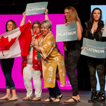 Convention-Photography Group of Canadian awardees holding a Canadian flag and "Congratulations Platinum" signs on stage during a Modere event, captured by Coldea Productions