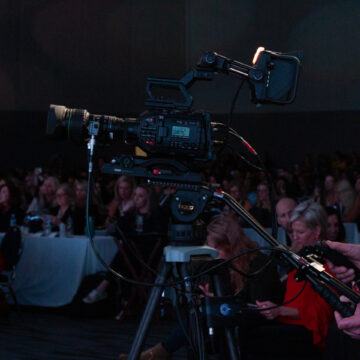 Convention-Photography Professional camera operator capturing a live audience event at a conference, with attendees attentively engaged.