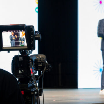 Convention-Photography Camera operator filming speakers on stage at the Scentsy conference, captured by Coldea Productions, showcasing professional event video production.