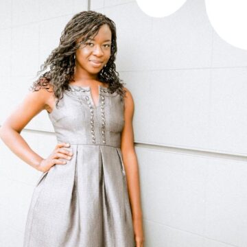 A confident woman posing in a stylish gray dress against a minimalist wall, highlighting Coldea Productions' expertise in portrait photography.