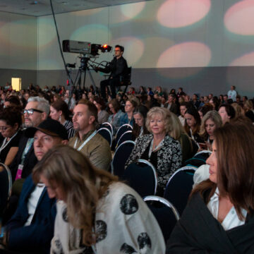 Conference-Photography Audience attentively watching a presentation at the Envision 20/20 conference, with a camera operator in view, captured by Coldea Productions.