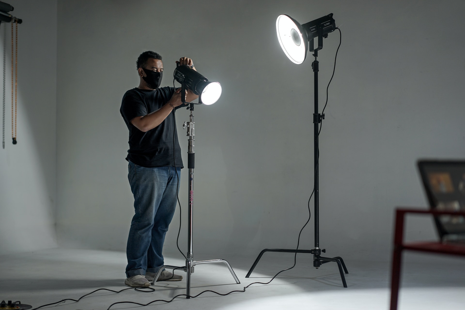 Production assistant adjusting studio lighting equipment in a professional setup.