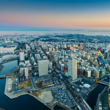 Aerial view of a coastal cityscape at sunset, highlighting urban architecture and waterfront, captured by Coldea Productions