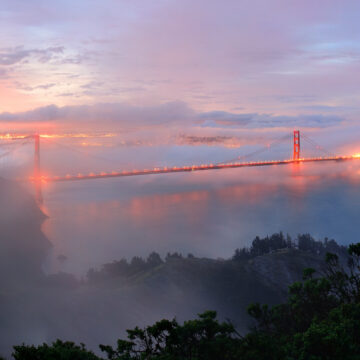Aerial view of the Golden Gate Bridge at sunrise, with mist and city lights, captured by Coldea Productions’ drone photography service.