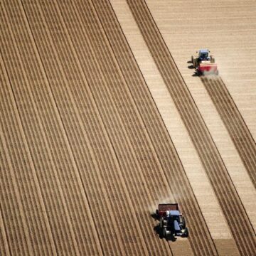 Aerial drone view of tractors working on a large farmland, provided by Coldea Productions' drone and aerial photography services