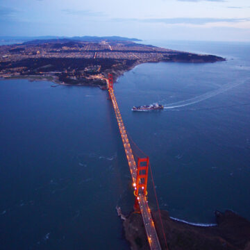 Aerial view of the Golden Gate Bridge at dusk with San Francisco cityscape in the background, captured by Coldea Productions