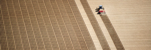 An aerial view of a tractor working on a vast agricultural field, representing Coldea Productions' expertise in aerial drone video production.