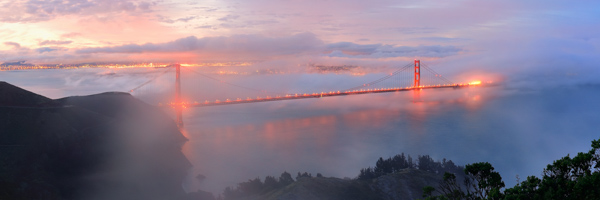 A stunning aerial view of the Golden Gate Bridge enveloped in fog during sunrise, representing Coldea Productions' expertise in aerial video production.