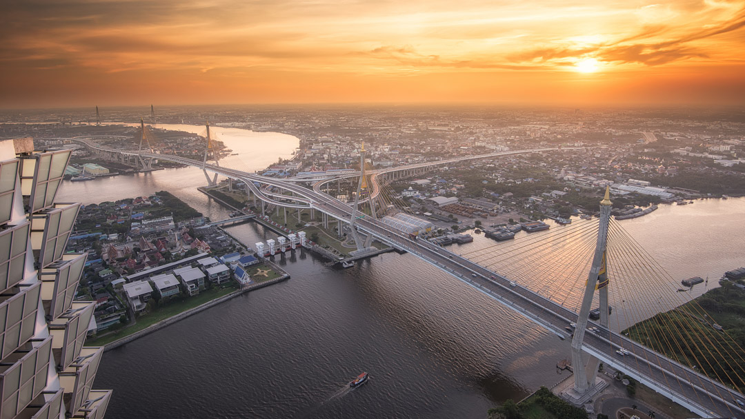 An aerial view of a sprawling urban landscape with bridges over a river at sunset, illustrating the beauty and complexity of aerial drone photography by Coldea Productions.