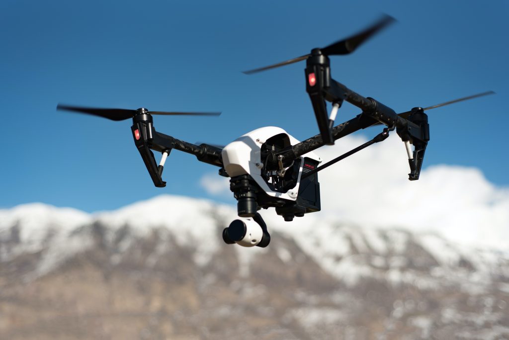 Close-up of a professional aerial drone in flight with mountain background, used for aerial photography and videography.