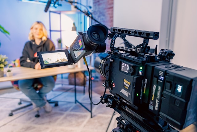 Professional video camera recording a woman during a marketing video shoot in a studio