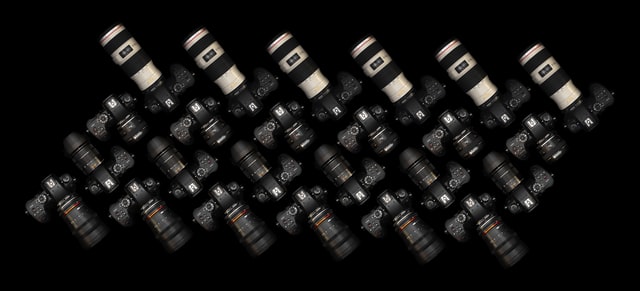 Collection of professional cameras and lenses arranged on a black background, showcasing the importance of proper gadget care for high-end equipment