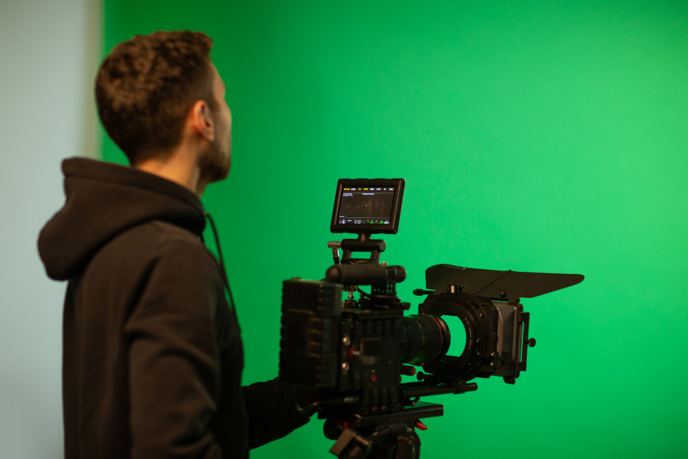 Cameraman operating a professional video camera in front of a green screen during a video shoot at Coldea Productions.