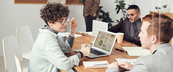 Colleagues in a business meeting discussing data on a laptop screen, illustrating Coldea Productions’ recruitment video production services for corporate environments.