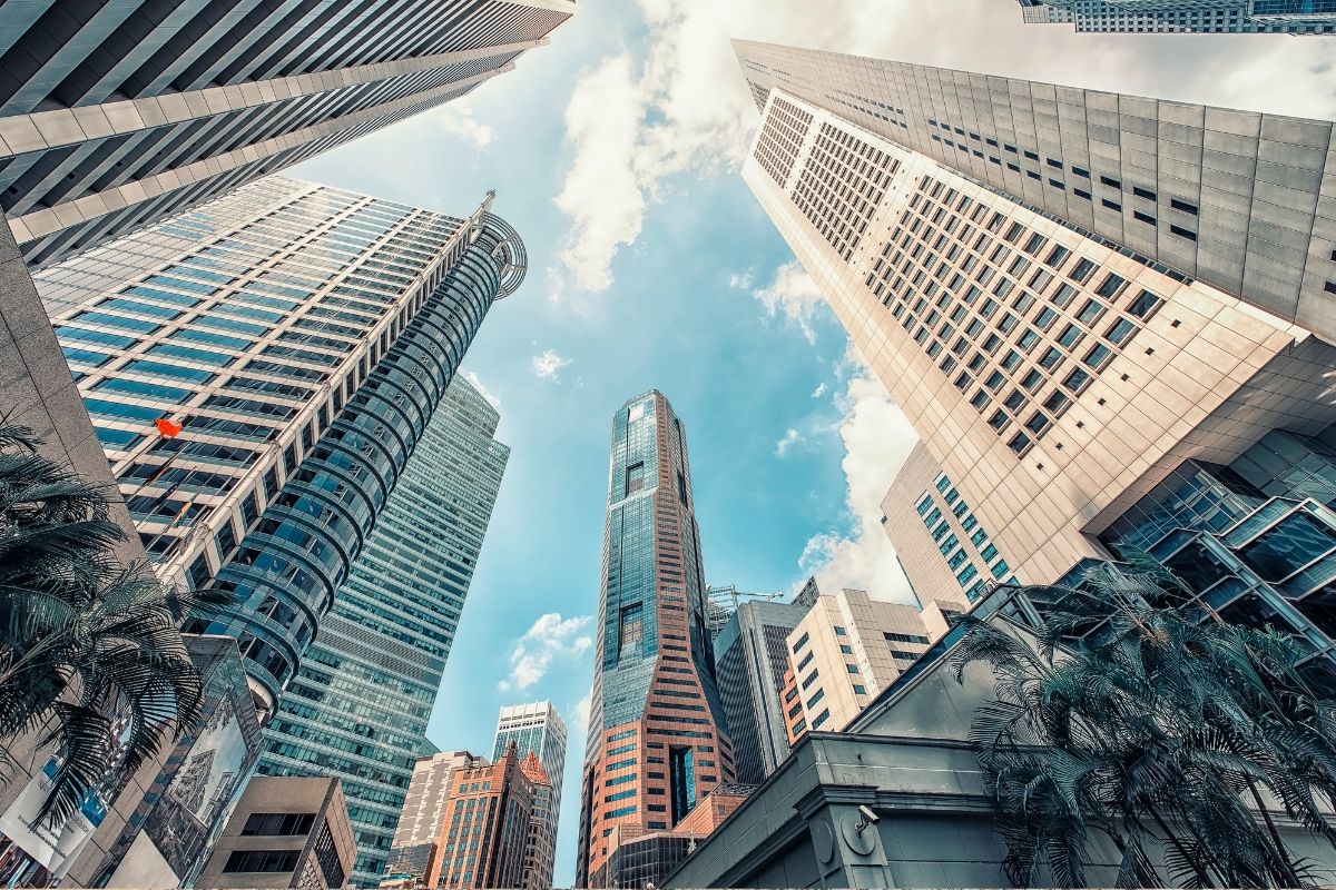 Low-angle shot of modern skyscrapers in a bustling city under a clear blue sky.