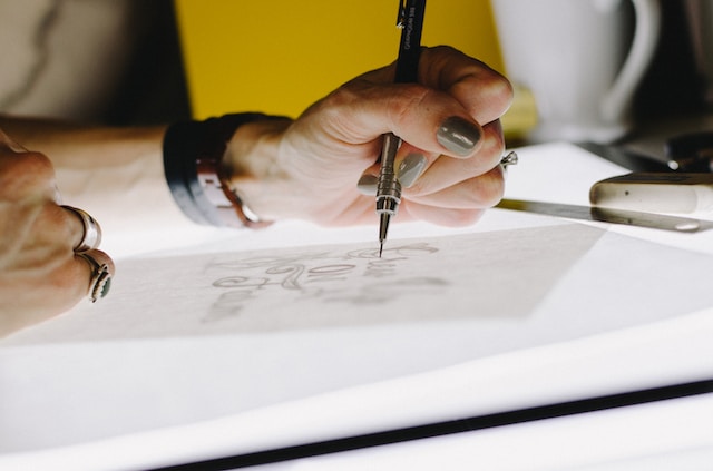 Design Tips for Business Logos, Designer sketching a business logo on paper using a mechanical pencil.