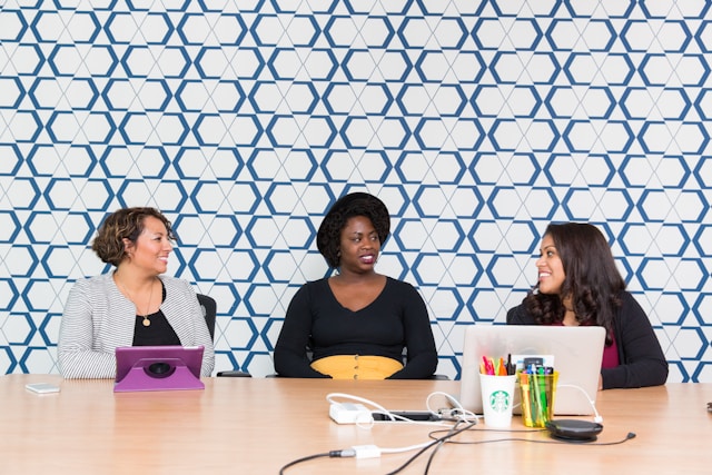 Three businesswomen having a meeting in a modern office, symbolizing teamwork and collaboration in e-commerce and video marketing strategies.