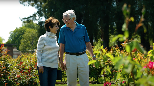 Elderly couple enjoying a walk in the garden, highlighting genuine moments of happiness and connection.