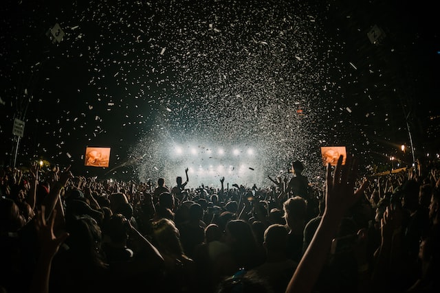 Energetic crowd at a music festival with confetti and bright stage lights, capturing the live event atmosphere.