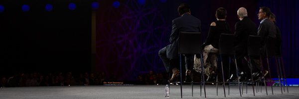 A convention stage with speakers presenting vibrant visuals to an engaged audience, captured by Los Angeles event photographers at Coldea Productions