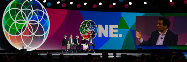 Coldea Productions capturing a panel discussion at a large-scale event with vibrant visuals and branding on stage.