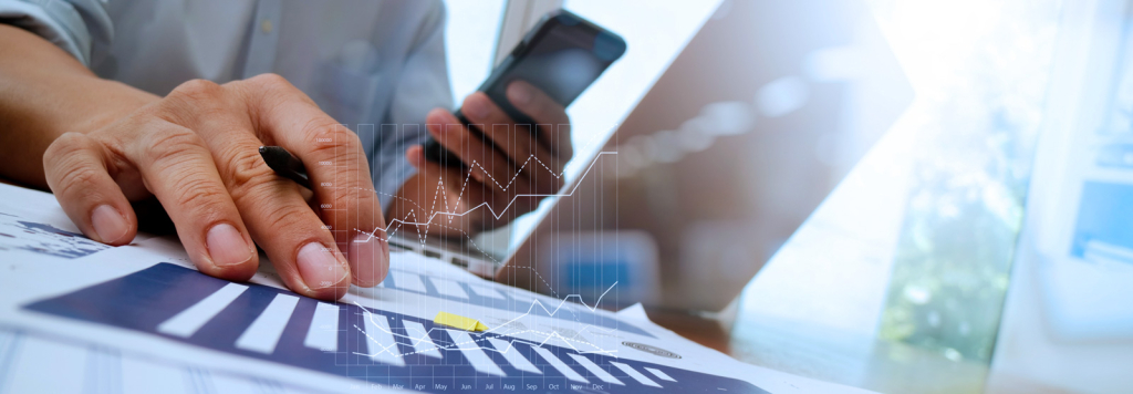 A professional analyzing data charts with a smartphone and laptop, representing Coldea Productions' expertise in producing web videos tailored to business needs.