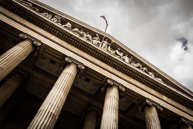 A close-up of the façade of a classical courthouse with tall columns and intricate sculptures under a cloudy sky.