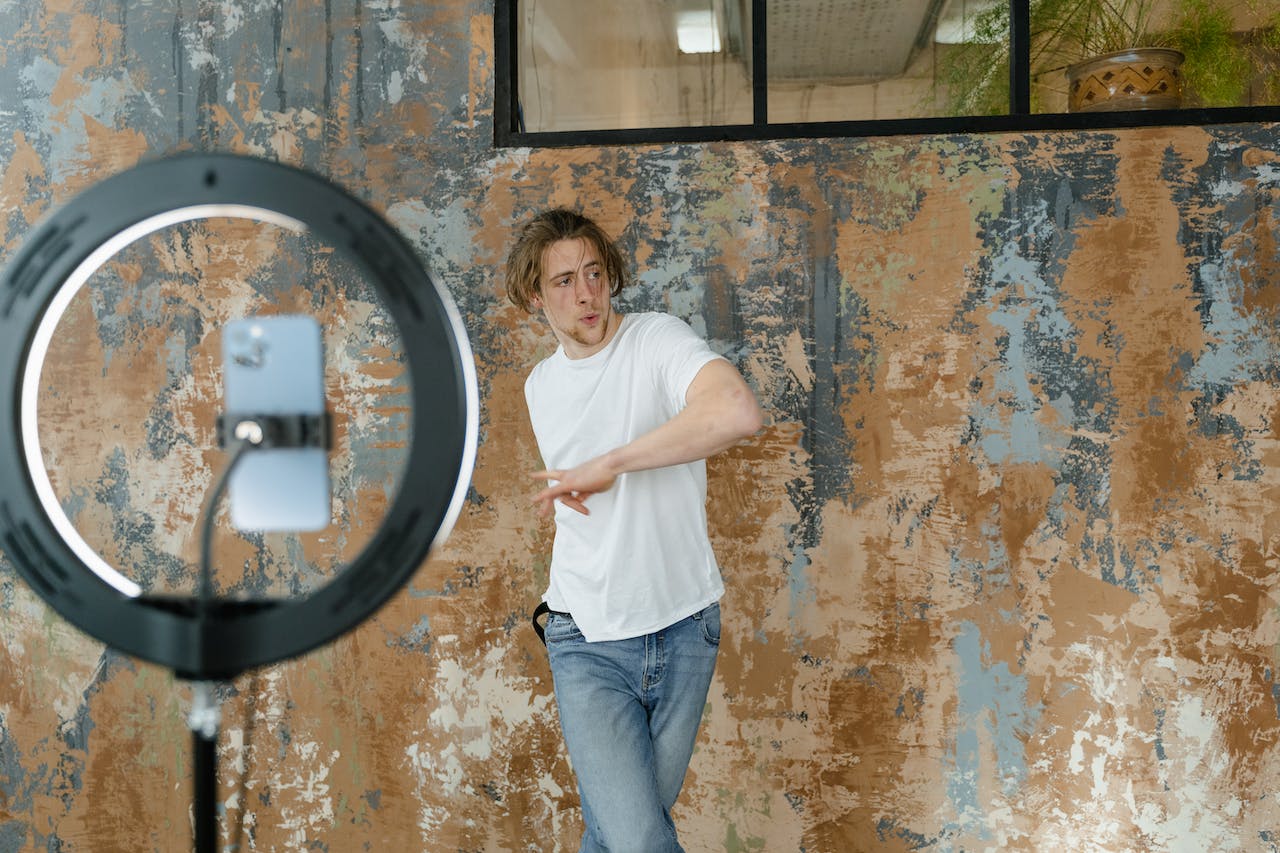 Influencer creating video content for SEO and social media, Man dancing in front of a smartphone camera on a tripod with a ring light, creating video content.