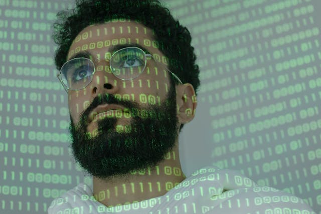 Man with binary code projected on face symbolizing the human side of cybersecurity and phishing defense.