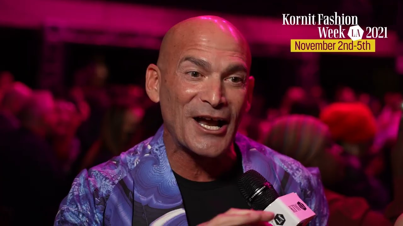 Ronen Samuel, CEO of Kornit Digital and a member of the Forbes Business Council, is seen giving an interview at Kornit Fashion Week LA 2021. He is wearing a vibrant purple jacket, and the event's logo and dates, "November 2nd-5th," are displayed in the top-right corner.