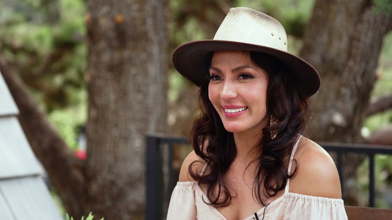 Priscilla, founder of Charlie James Artisan, wearing a hat and smiling during a small business spotlight video interview about her story-driven jewelry brand.
