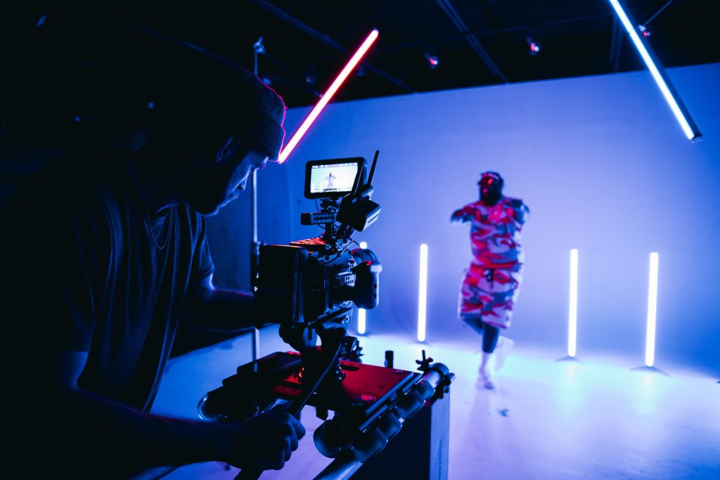 Videographer filming an artist in a studio with neon lighting, representing creative video production.