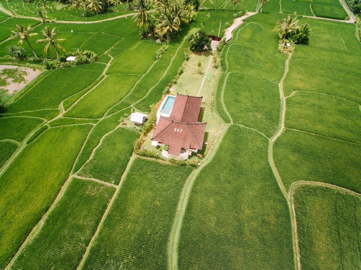 Aerial view of a countryside home surrounded by lush green fields, showcasing rural real estate.