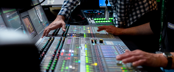 Close-up of technicians operating an advanced sound mixing board during a live-stream event by Coldea Productions.
