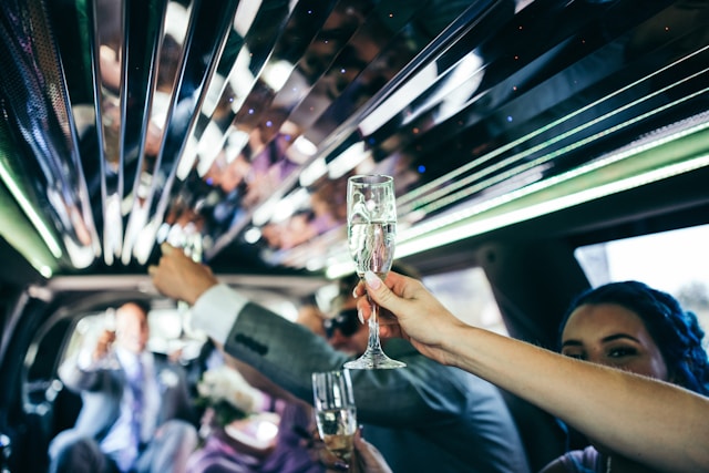 Person holding a clear wine glass in a limo, highlighting luxury and celebration.