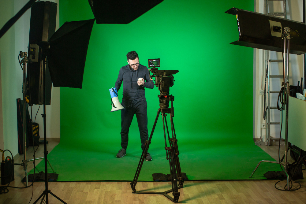 Person holding a megaphone on the set of Coldea Productions in front of a green screen during a video shoot with professional lighting and camera setup.
