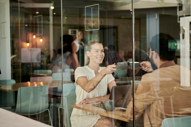 Smiling woman greeting a client in a modern café, symbolizing how professional photography creates warm first impressions and authentic brand connections by Coldea Productions.