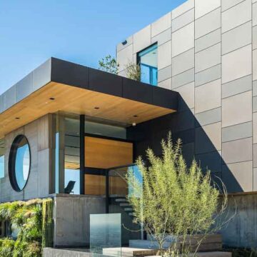 A modern architectural home with unique design features, including a circular window and green wall accents, showcasing real estate photography by Coldea Productions.