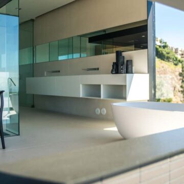 Modern, luxurious bathroom with large glass windows and minimalist decor, highlighting real estate photography by Coldea Productions.