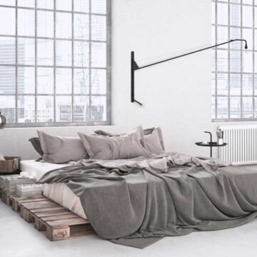 Modern minimalist bedroom with large industrial windows and neutral decor, showcasing Coldea Productions' real estate photography services.