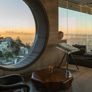 Luxurious living room with a circular window view of the city skyline at sunset, showcasing real estate photography by Coldea Productions.