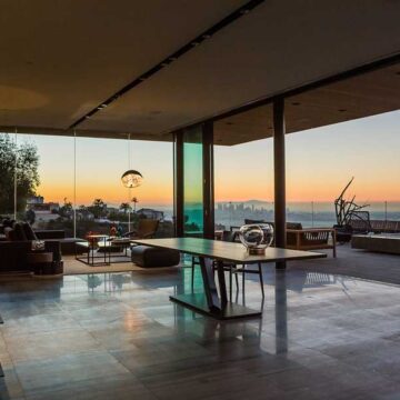 Interior view of a luxury home with floor-to-ceiling windows showcasing a sunset view, photographed by Coldea Productions