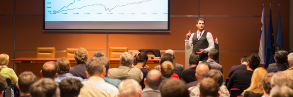 A corporate trainer presenting data trends using a projection screen during a professional training session in a modern conference room.