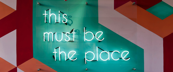 Neon sign reading "this must be the place," symbolizing Coldea Productions as the go-to company for professional video animation services.