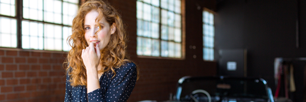 Model posing in a naturally lit studio with a classic car, representing Coldea Productions' video commercial services in Los Angeles, California