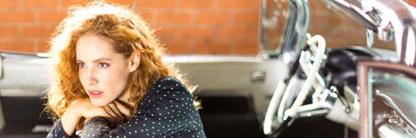 Close-up of an actress in deep thought, sitting beside a vintage convertible during a video production shoot in San Diego, California.